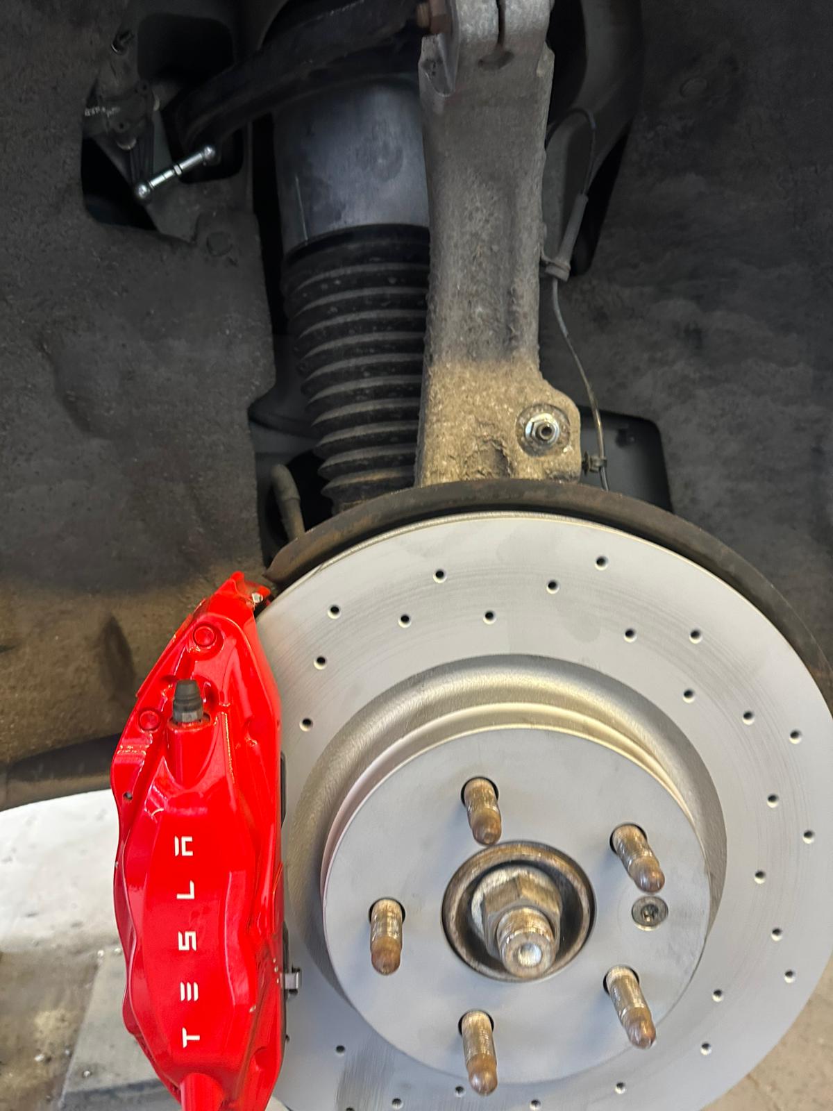 Tesla-bromsskiva och röd Tesla-bromsok under service hos Pro Cars