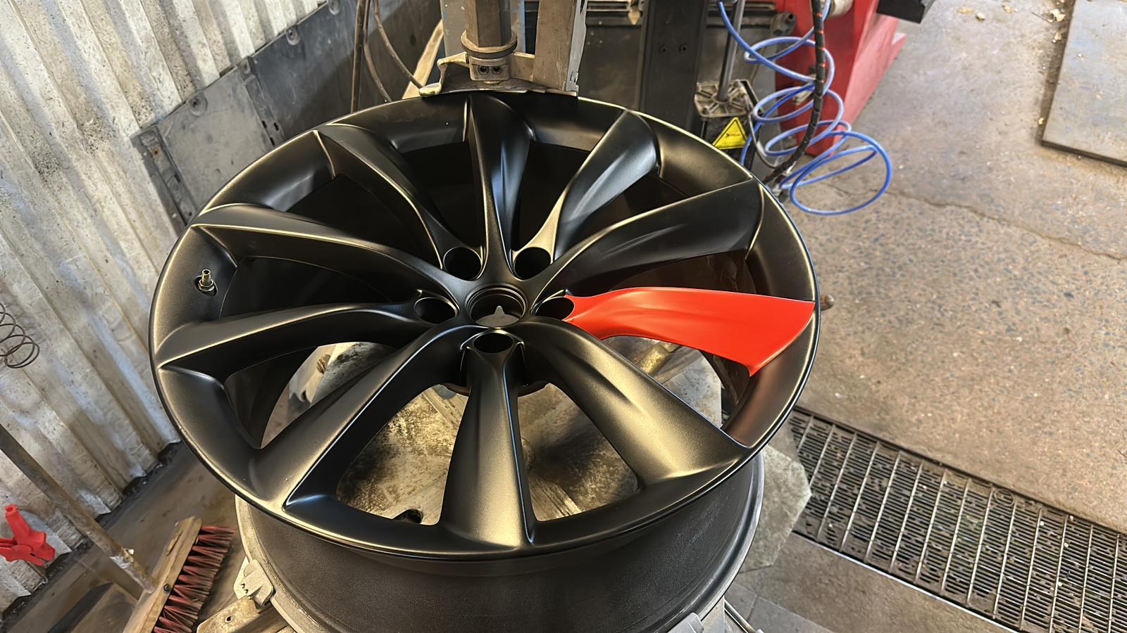 Tesla-fälg efter renovering med matt svart finish och röd accentdetalj