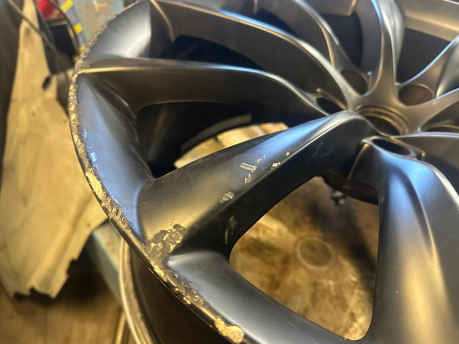 Skadad Tesla-fälg före renovering — närbild på trottoarskador