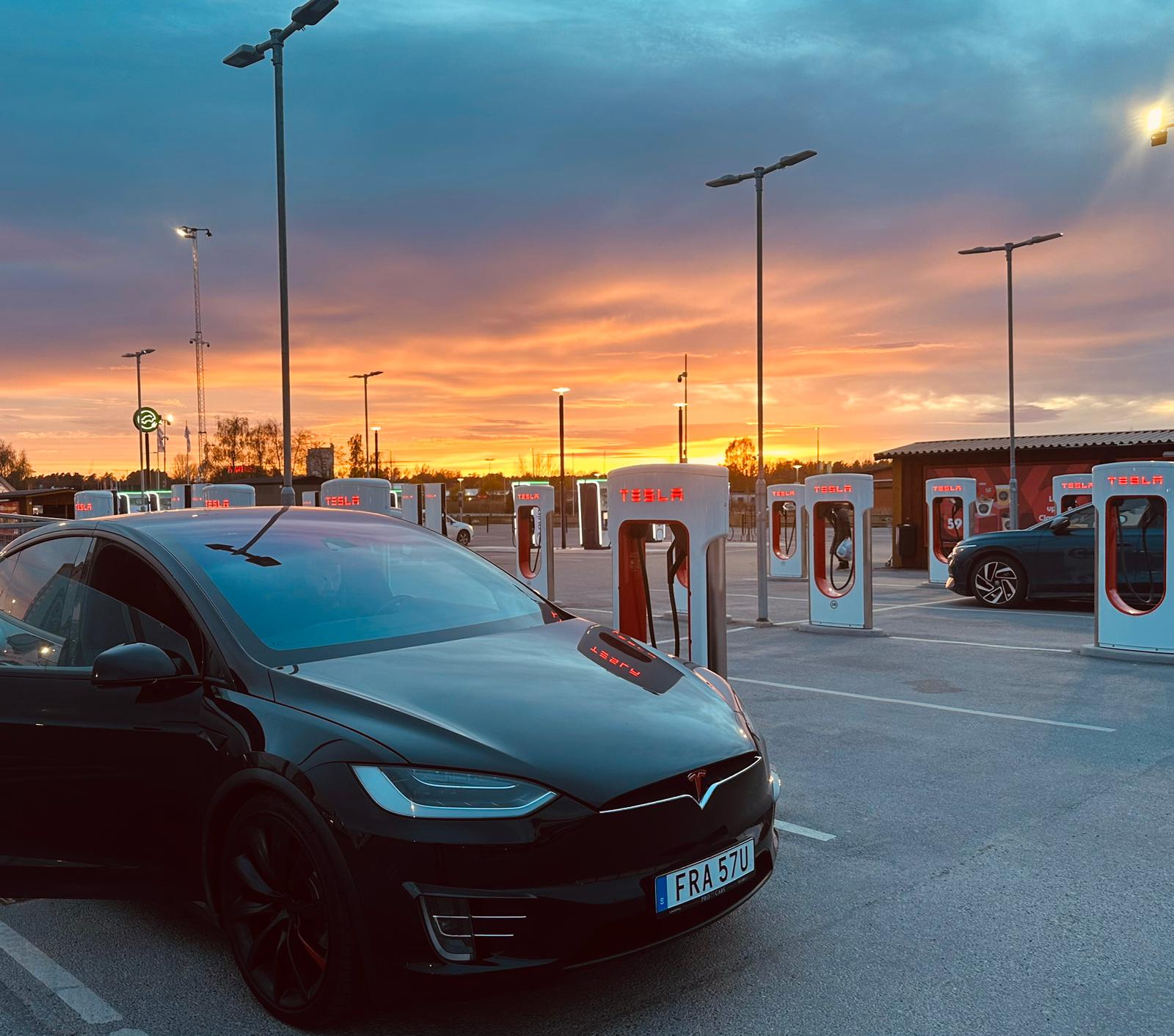 Tesla vid Supercharger i solnedgång